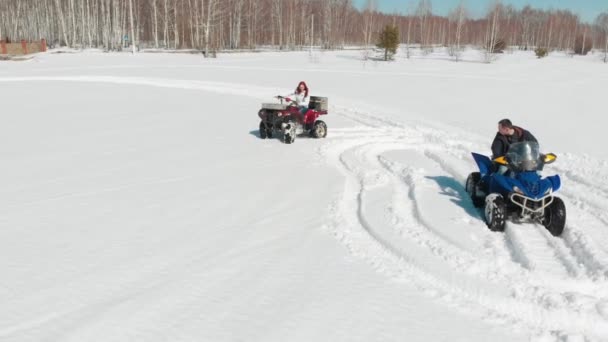 Een man en een vrouw rijden Quad fietsen een na de andere door de sneeuw - Video