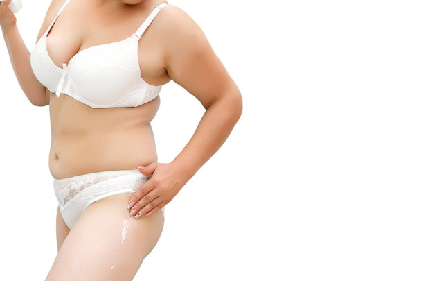 a woman with excess weight applying cream on the hips - Photo, Image