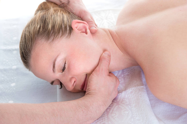 As mãos dos homens fazem uma massagem terapêutica no pescoço para uma garota deitada
  - Foto, Imagem