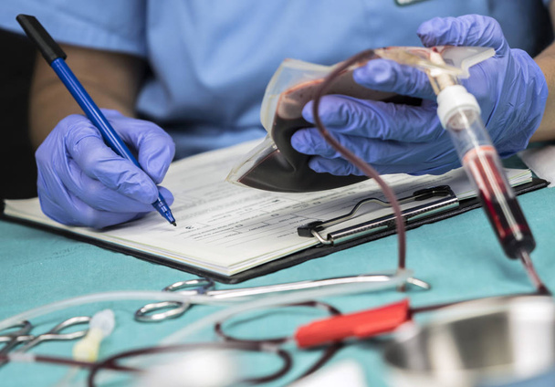 Enfermeira tira dados de um saco de sangue em um hospital, imagem conceitual
 - Foto, Imagem