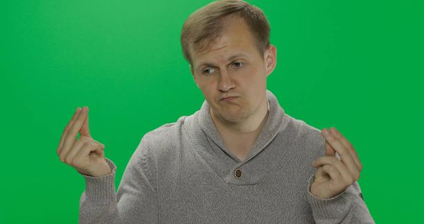 Handsome young man in sweater doing no money gesture. Poverty. Chroma key - Photo, Image