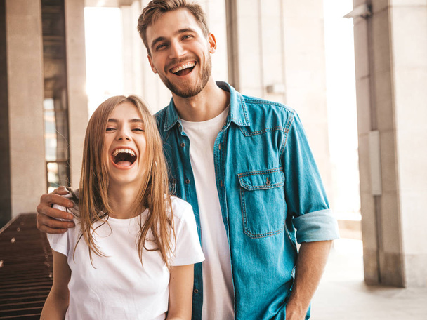 Portrait of smiling beautiful girl and her handsome boyfriend. Woman in casual summer jeans clothes. Happy cheerful family. Female having fun on the street background - 写真・画像