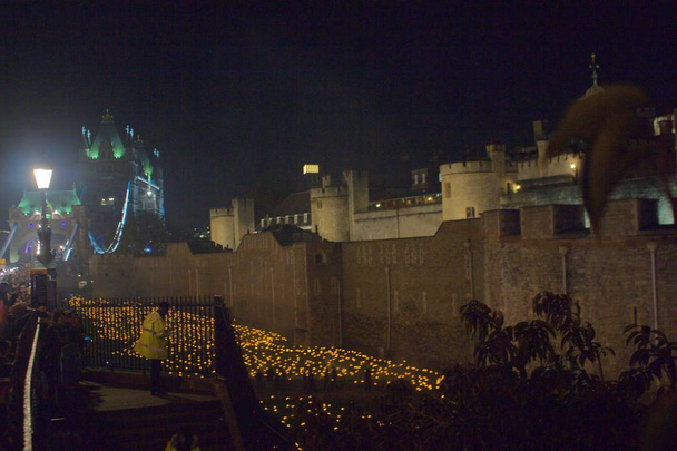 Νυχτερινή θέα του εκατονταετηρίου μνημείου στον πύργο του Λονδίνου για να σηματοδοτήσει το τέλος του Παγκοσμίου πολέμου ένα, φλόγα, δαυλούς, κεριά, απομνημόνευση των πεσόντων, Πύργος γέφυρα στο παρασκήνιο - Φωτογραφία, εικόνα