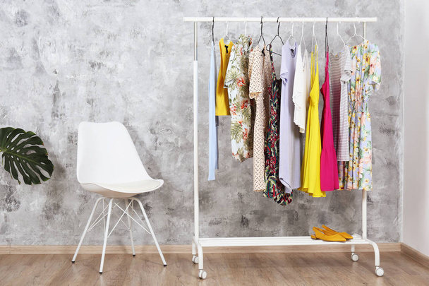 Women's hip clothing store interior concept. Row of different colorful female clothes hanging on rack in hipster fashion show room in shopping mall. Grunged concrete wall background. Copy space. - Fotoğraf, Görsel