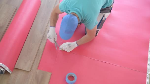 木製の床パネルインストーラ。30代の白人改造労働者が新しいフロアを設置. - 映像、動画