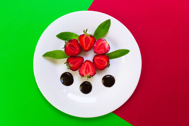 Erdbeeren in Schokolade und Minzblättern. roter und grüner Hintergrund, Draufsicht. - Foto, Bild