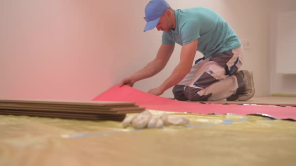 Remodeling munkavállaló a 30-as évek telepítése új fa padló. Padlópanelek telepítő. - Felvétel, videó