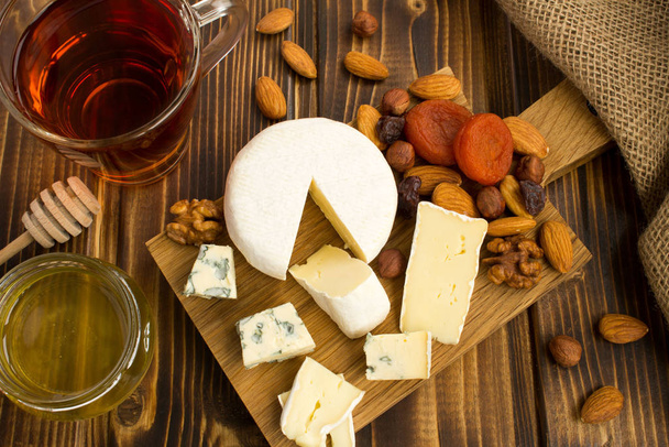 Snack avec fromages, thé et miel sur la planche à découper en bois.Vue d'en haut
. - Photo, image