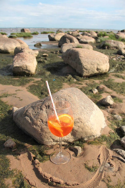Великий келих з коктейлем на кам'яному узбережжі
 - Фото, зображення