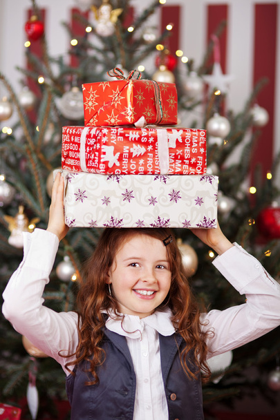 Laughing girl with Christmas gifts on her head - Фото, изображение