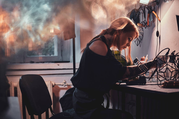 Επιμελής γυναίκα εργάζεται για το δικό της έργο στο εργαστήριο γυαλιού. - Φωτογραφία, εικόνα