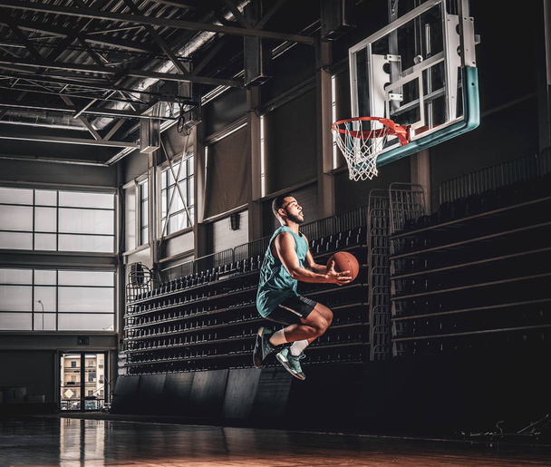 Μαύρος παίκτης μπάσκετ σε δράση σε γήπεδο μπάσκετ. - Φωτογραφία, εικόνα