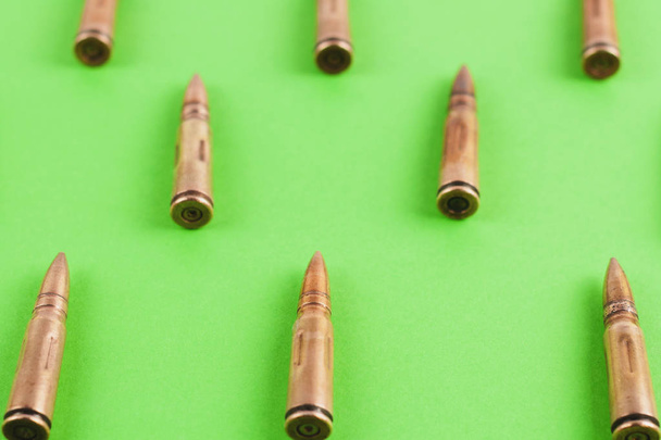 Row of many metal bullets for assault rifle on green background - Фото, зображення