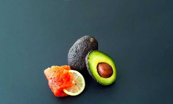 The concept of organic food.Salmon fillet and avocado on dark ba - Foto, afbeelding