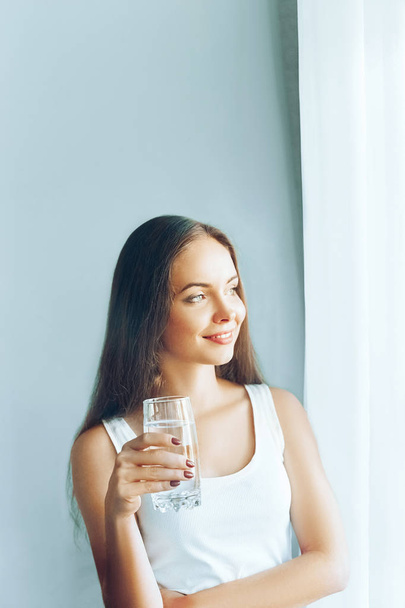 Healthy lifestyle.Young woman drinking from a glass of  fresh water. Healthcare. Drinks. Portrait of happy smiling female model holding transparent glass. Health,Beauty,Diet concept. Healthy eating. - 写真・画像