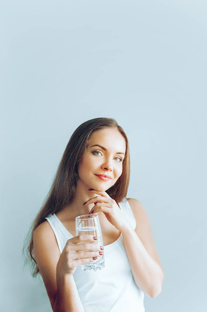 Healthy lifestyle. Young woman show glass of water. Girl drinks water. Portrait of happy smiling female model  holding transparent glass of water. Health,Beauty, Diet concept - Zdjęcie, obraz