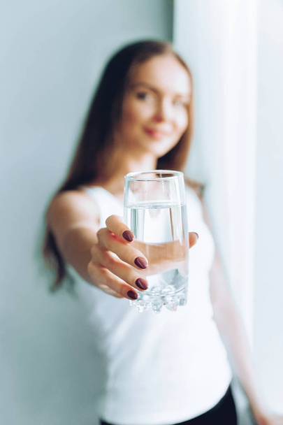 Closeup young woman show glass of water. Portrait of happy smiling female model  holding transparent glass of water.Healthy lifestyle. Beauty, Diet concept - Zdjęcie, obraz