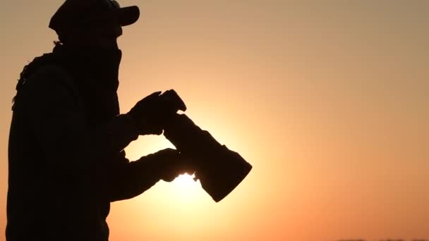 Safari kültéri fotós a Sunset. Sziluettje férfi vezetése digitális fényképezőgép a kézben nagy teleobjektív a jobb Wildlife closeups. Lassú mozgás Footage - Felvétel, videó