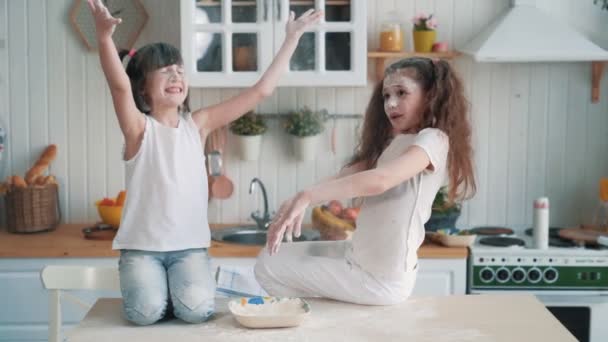 Cute sisters throwing flour at each other, have fun time at kitchen, slow motion - Imágenes, Vídeo