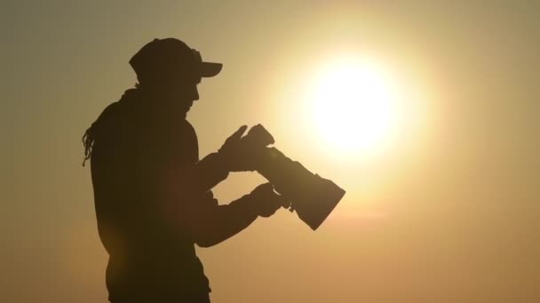 Fotógrafo ao ar livre equipado com grandes lentes telefoto na localização remota durante o pôr do sol cênico
. - Filmagem, Vídeo