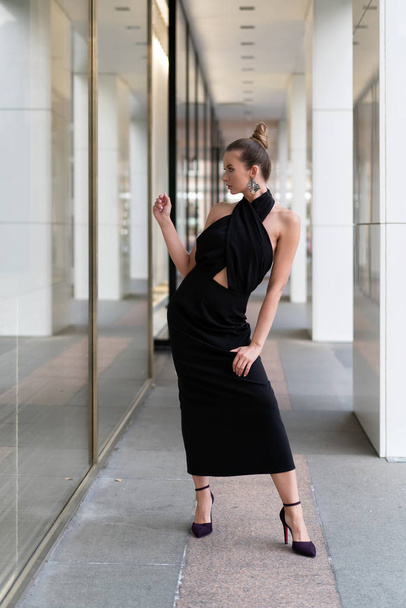 European model originally posing in a black dress near the boutique. In the glass you can see its reflection. Very stylish interesting atmosphere for advertising fashion trends. - 写真・画像