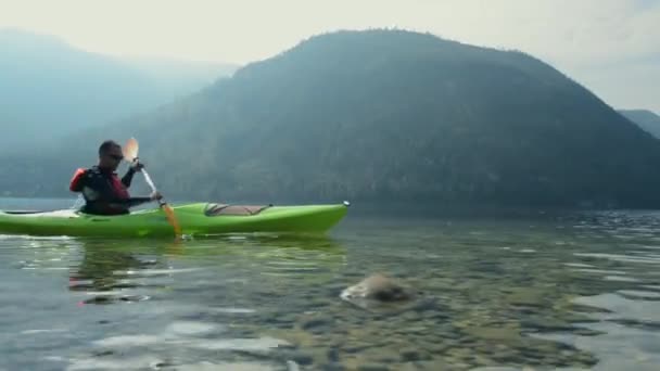 Kajaktocht op het schilderachtige meer. Kaukasische kayaker peddelen in zijn kajak. - Video