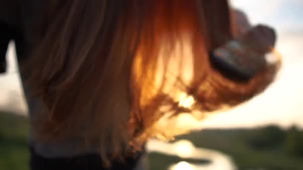 Czerwone długie włosy dziewczyny z bliska podczas czesania o zachodzie słońca w zwolnionym tempie - Materiał filmowy, wideo