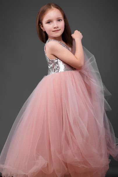 Little girl in a pink dress, with a beautiful hair. - Foto, Bild