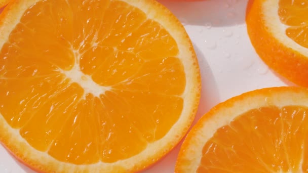 Sliding along oranges slices on a white and wet background - Materiaali, video