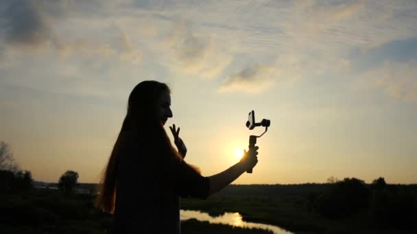 Chica blogger dispara vídeo selfie en el teléfono inteligente con estabilizador en cámara lenta
 - Imágenes, Vídeo