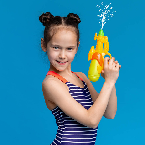 Girl in swimwear shooting up with water gun - Photo, Image