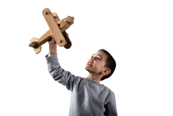 Kid plays with a wooden toy airplane. Isolated on white background - Photo, image