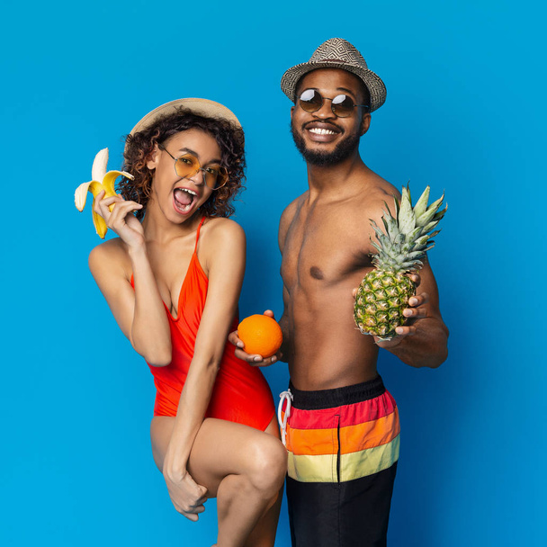 Gelukkig Afrikaans meisje en man genieten van banaan, sinaasappel en ananas - Foto, afbeelding