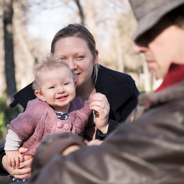 Νεαρή οικογένεια με χαρούμενο παιδί στο πάρκο. - Φωτογραφία, εικόνα