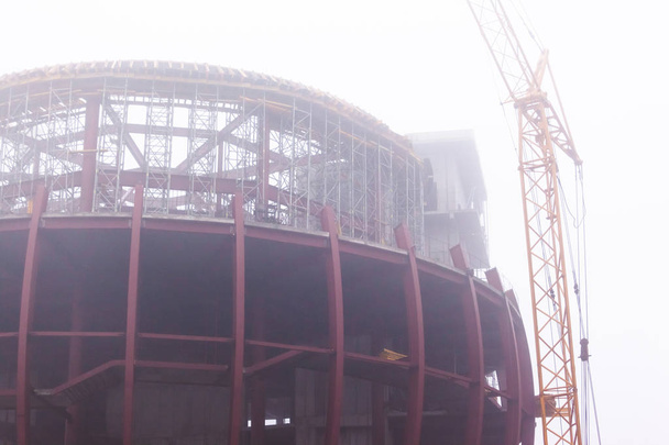 строительные краны в густом тумане рядом с большой конструкцией балки
 - Фото, изображение