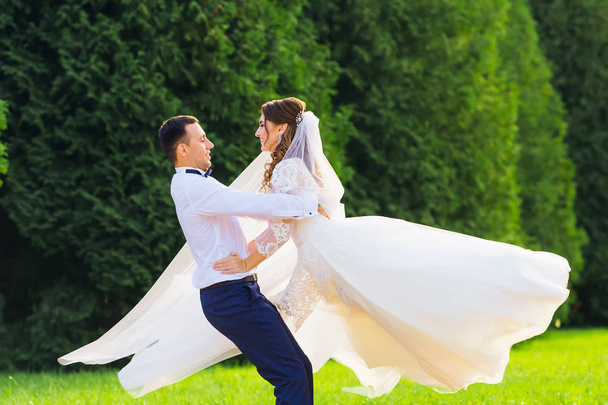 ο γαμπρός αγκάλιασε τη νύφη πίσω από τη μέση και στροβιλίζονται σε - Φωτογραφία, εικόνα