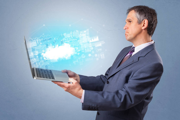 Man holding laptop with cloud based system notifications - 写真・画像