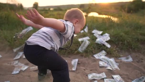 Χαριτωμένο αγόρι πετάει καλά μια τεράστια στοίβα των χαρτονομισμάτων δολαρίων στο έδαφος, αργή κίνηση - Πλάνα, βίντεο