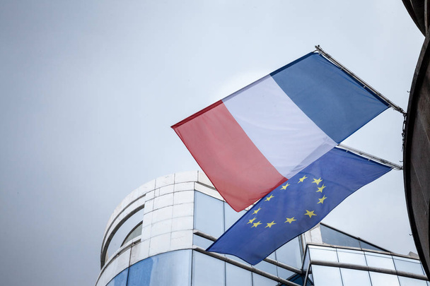 Bandeira francesa e bandeira da União Europeia em pé em frente a um edifício de negócios, renúncia. A França é um dos principais intervenientes e membros da UE
 - Foto, Imagem