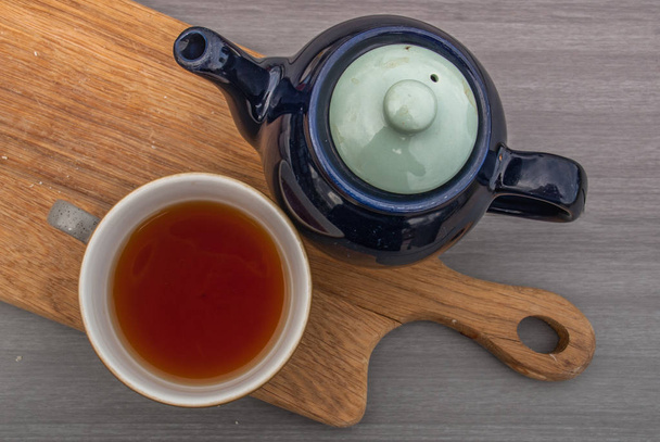 Cup of tea with teapot on a wooden table. - Fotoğraf, Görsel