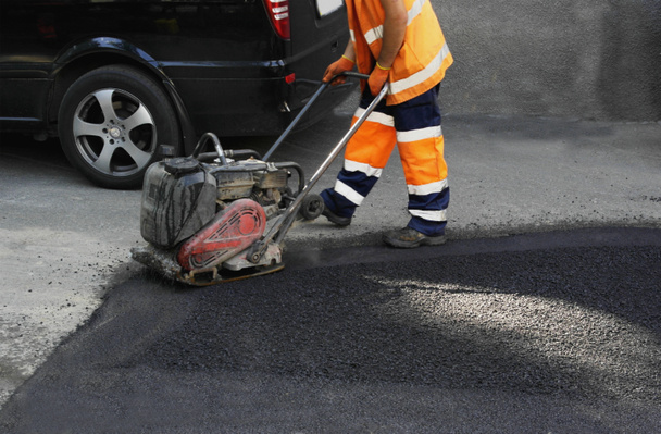 Plate compactors asphalt laying. Laying asphalt, covering the pit, on the rubble. - Photo, Image
