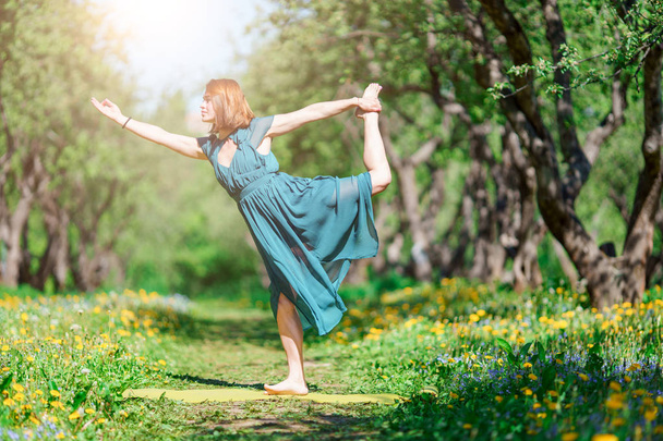 Image of woman in long green dress doing yoga in forest - Foto, Bild