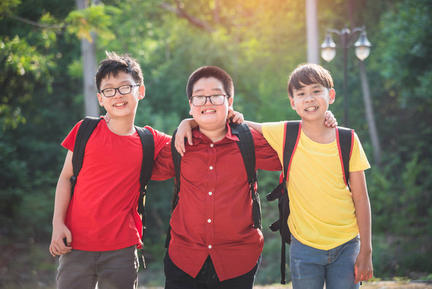 Trois écoliers debout et souriants ensemble à l'école
  - Photo, image