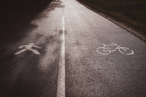 Асфальтований шлях, розділений на дві частини - одна частина для велосипедистів, інша для пішоходів
. - Фото, зображення
