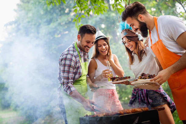 Happy friends making barbecue and having lunch in the nature - Foto, Imagem