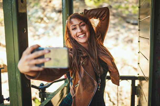 νεαρή χαμογελαστή γυναίκα κάνει selfie σε ρετρό τρένο  - Φωτογραφία, εικόνα