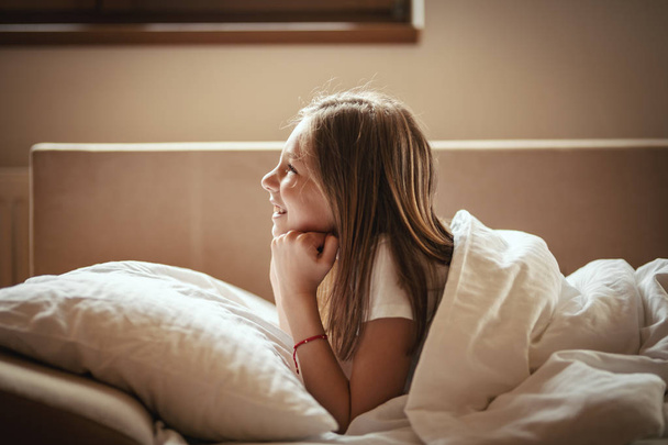 Gelukkig meisje liggend op bed in de ochtend - Foto, afbeelding