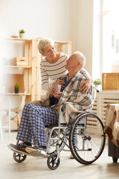 Full length portrait of senior woman caring for husband sitting in wheelchair, copy space - Photo, Image