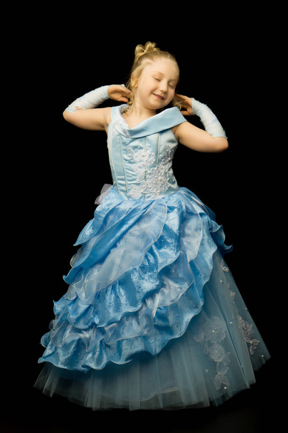 A little girl in a long, elegant dress of a princess on a black  - Fotoğraf, Görsel
