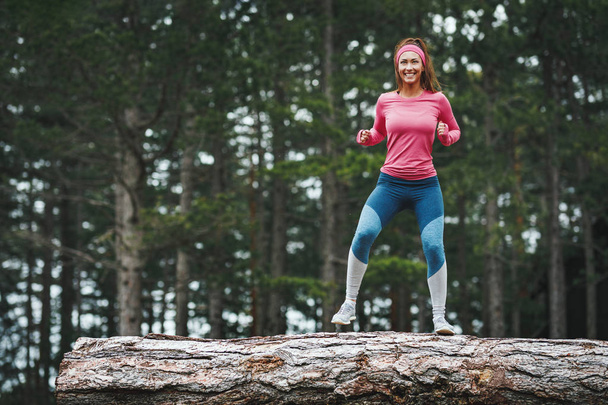 Fiatal vidám női futó edzés öreg fatörzs az erdőben - Fotó, kép